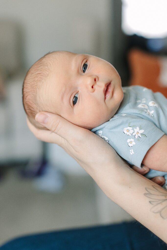 Baby being held by mom during in-home newborn photography session in Michigan