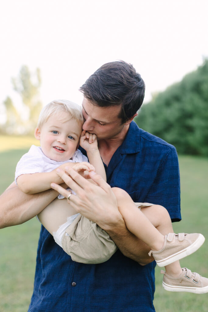 Father holding their children during a natural outdoor family portrait session in Lansing, Michigan.