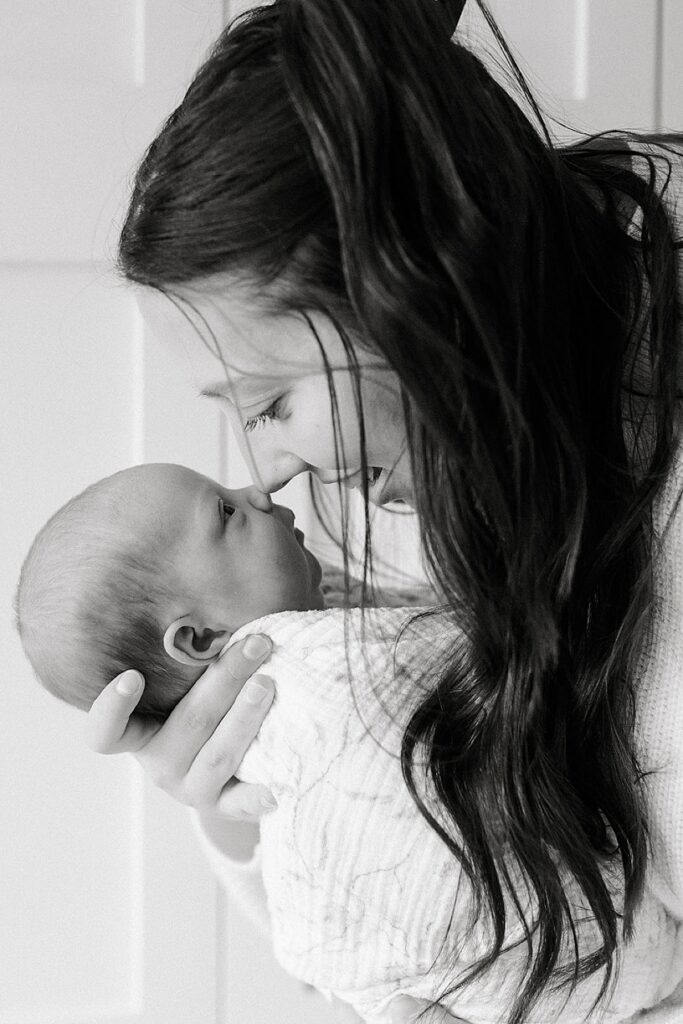 Parents admiring their newborn baby during a cozy in-home newborn photography session with a Michigan newborn photographer.