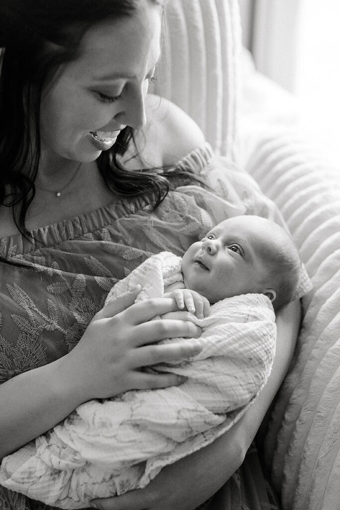 Mother holding her newborn baby in the nursery during a cozy in-home newborn photography session in Michigan.