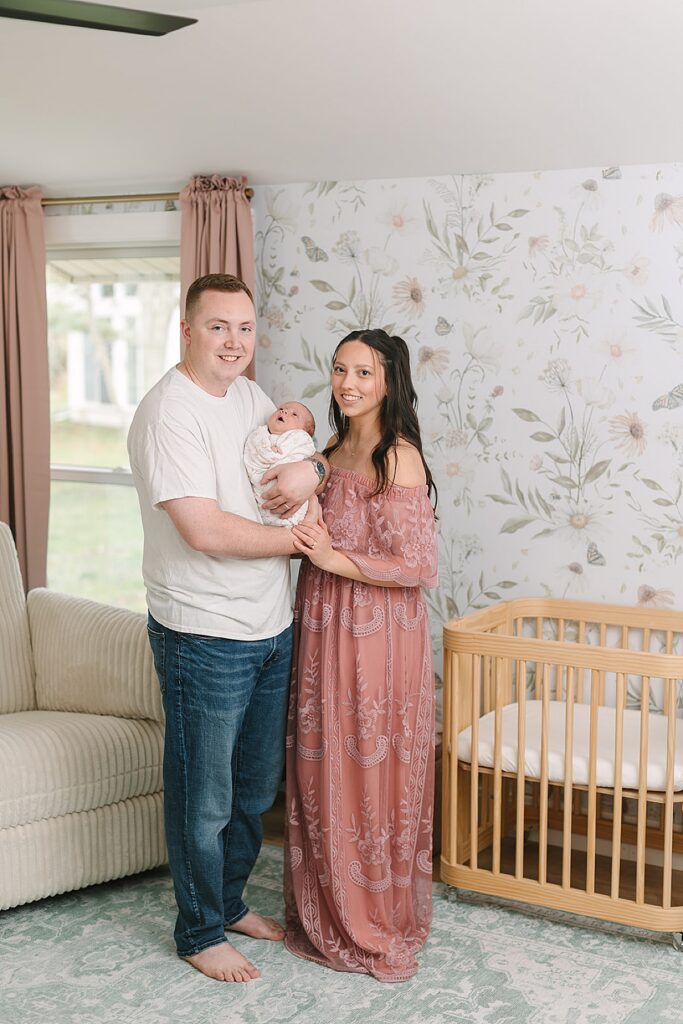 New parents smiling at their newborn baby together in the nursery during an in-home newborn photography session.