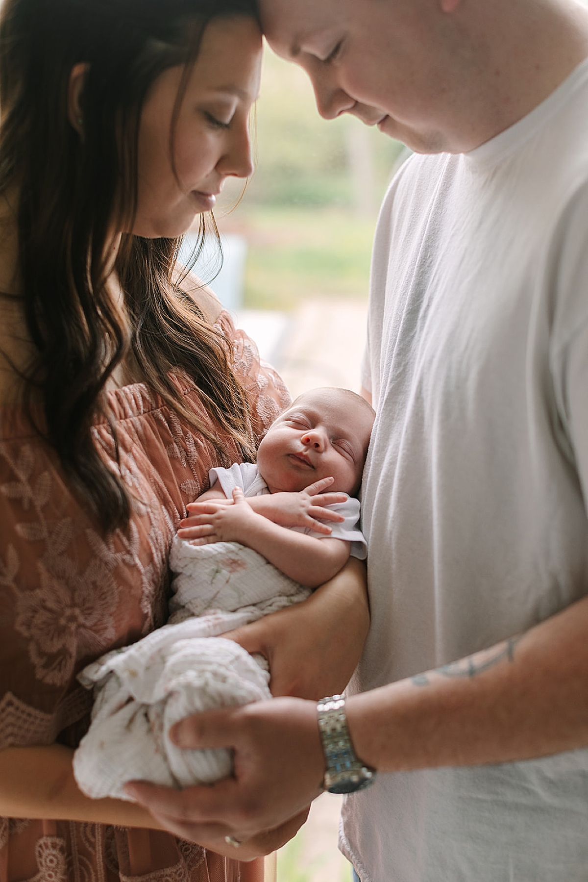 New parents smiling at their newborn baby together in the nursery during an in-home newborn photography session.