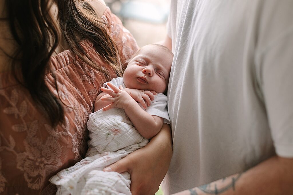 New parents smiling at their newborn baby together in the nursery during an in-home newborn photography session.