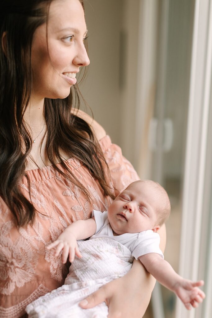 Mother holding her newborn baby in the nursery during a cozy in-home newborn photography session in Michigan.