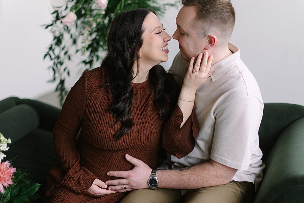 Couple posing in a floral installation during a winter maternity photography session with a Michigan maternity photographer.