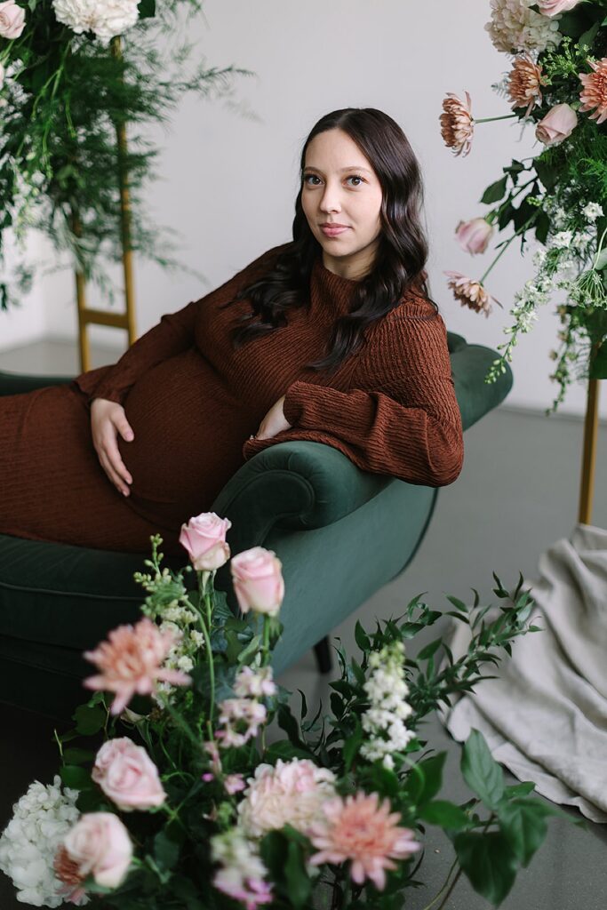 Couple posing in a floral installation during a winter maternity photography session with a Michigan maternity photographer.