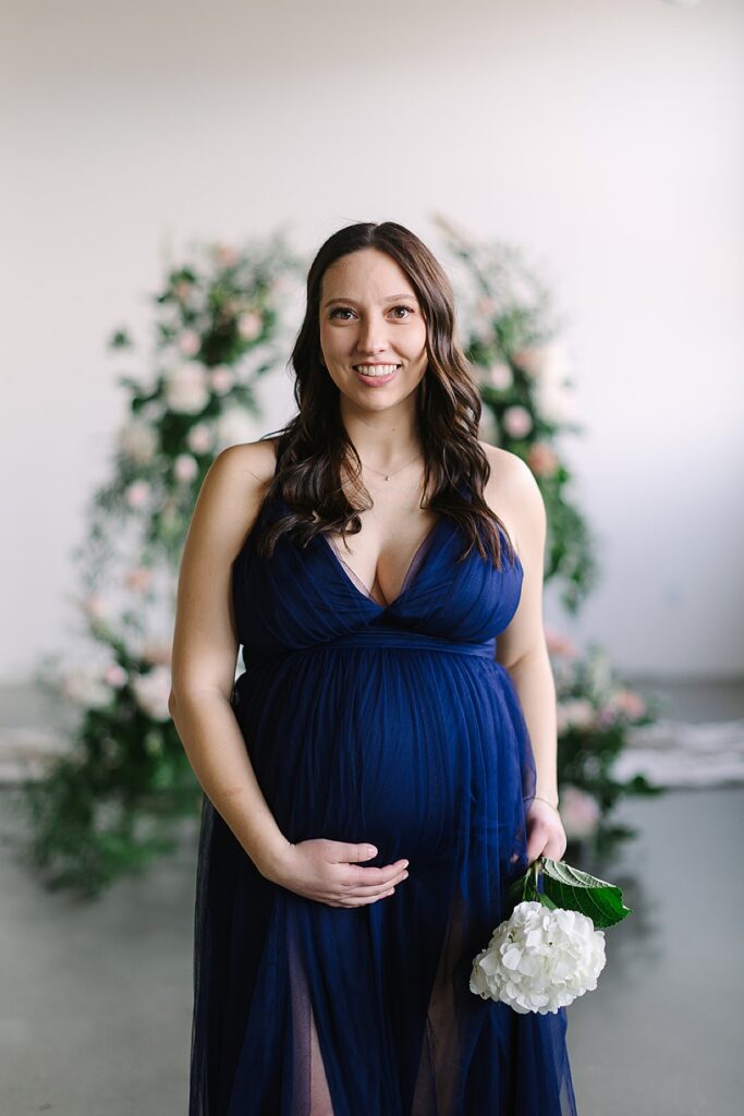 Couple posing in a floral installation during a winter maternity photography session with a Michigan maternity photographer.