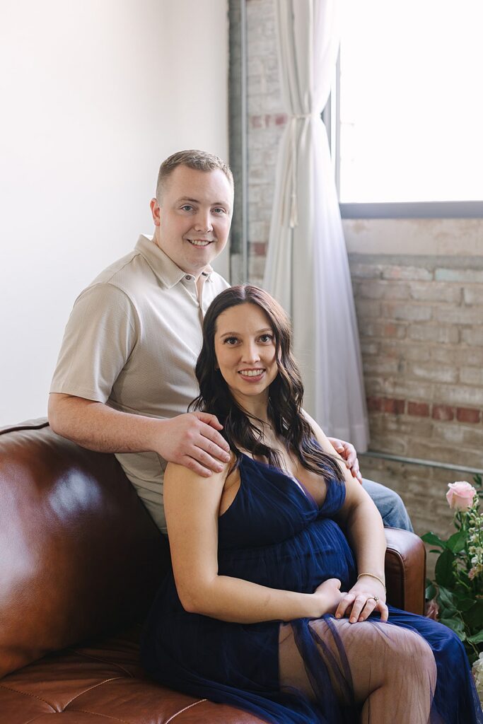 Couple posing in a floral installation during a winter maternity photography session with a Michigan maternity photographer.