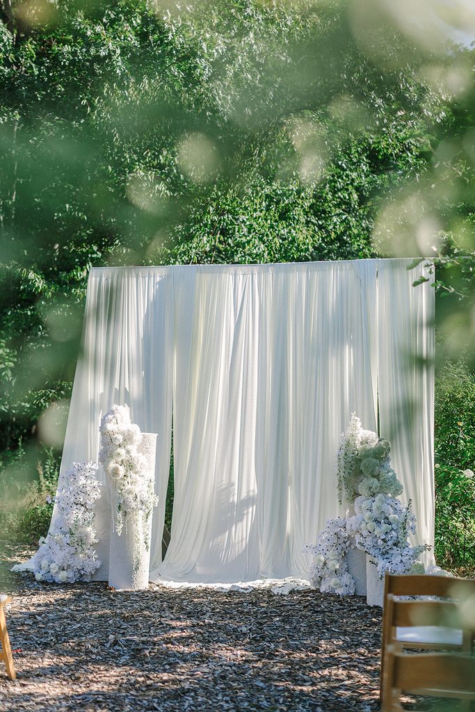 Flowy white wedding ceremony backdrop with luxurious statement floral installs