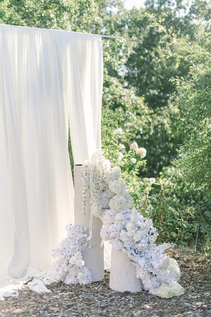 Flowy white wedding ceremony backdrop with luxurious statement floral installs