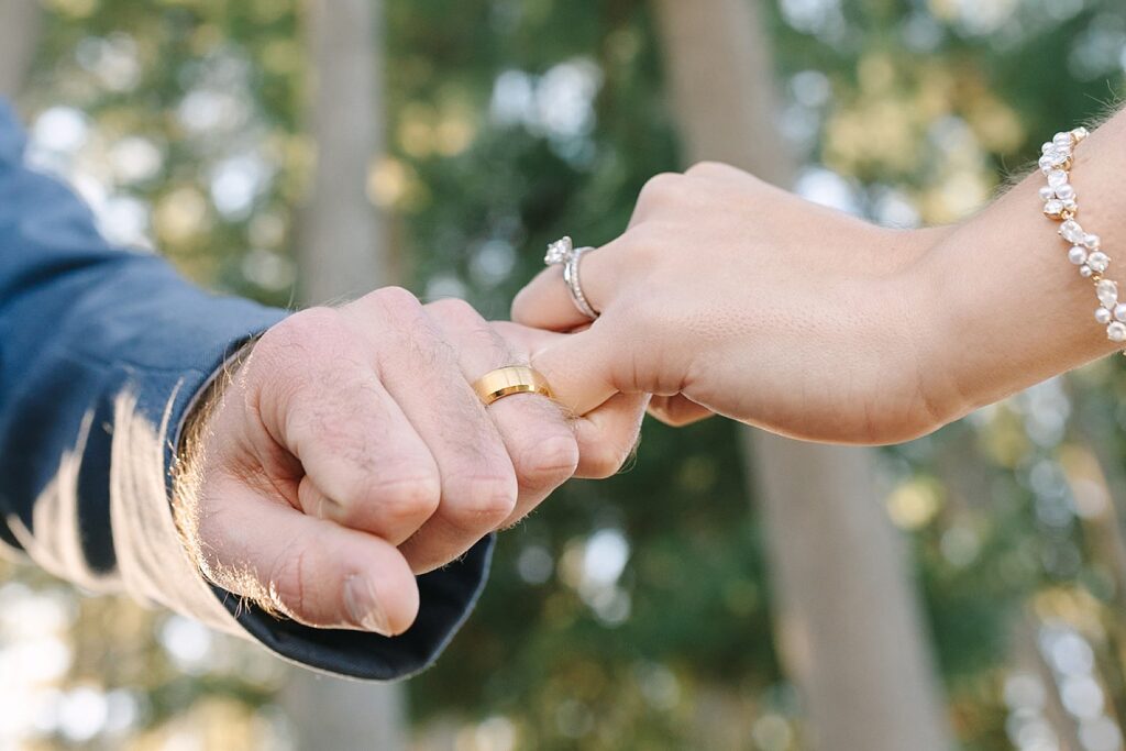 Aerin and Jack's wedding rings beneath the pines at Michigan State University