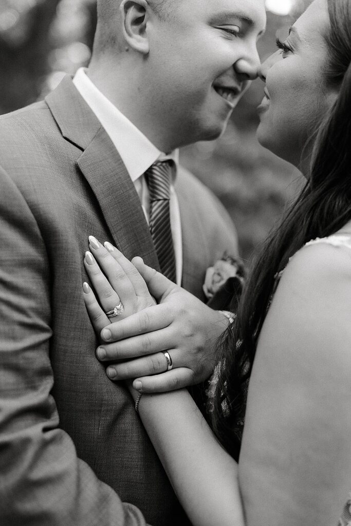 black and white bride and groom portrait showing off their rings during golden hour