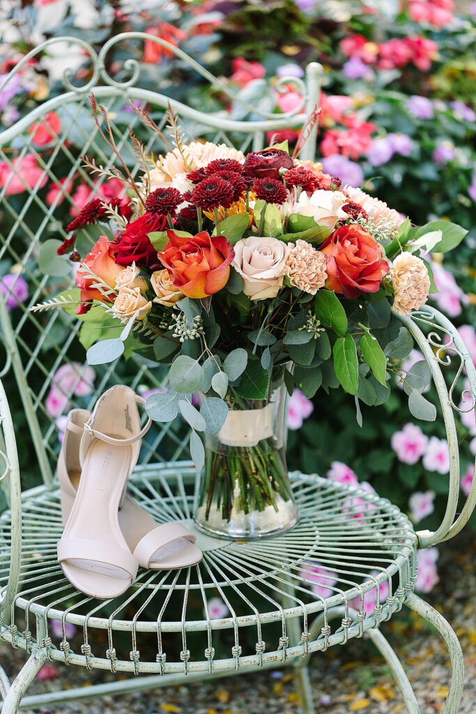 brides nude colored open toed shoes next to her fall inspired wedding bouquet on a vintage green metal chair