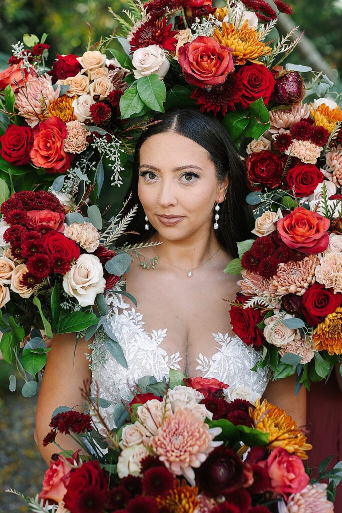 bridal portrait during golden hour with bridesmaids bouquets framing her face