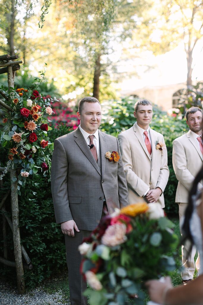 grooms smiling at bride while shes walking down the at everlastings in the wildwood wedding venue