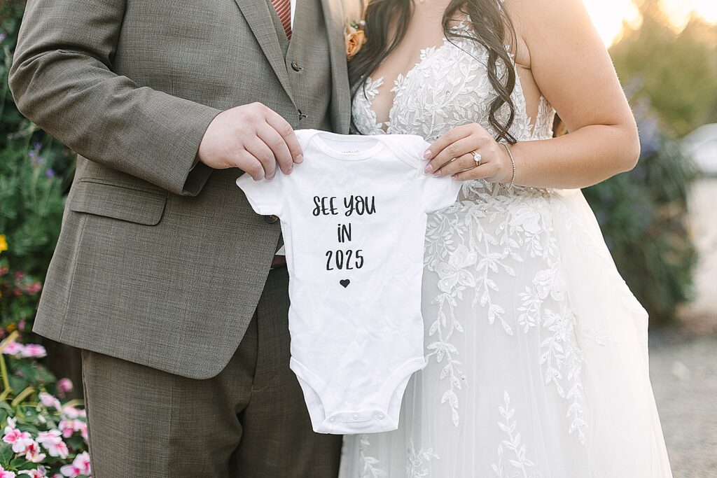 bride and groom announce their pregnancy at their wedding using a baby onsie