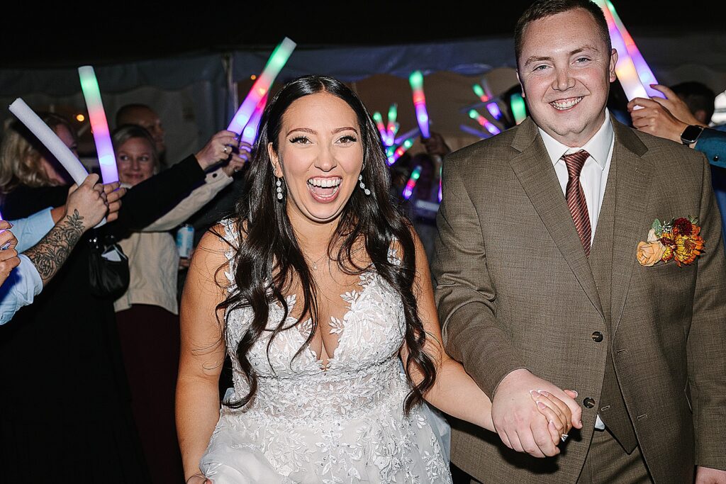 bride and groom exit their wedding reception with glow sticks